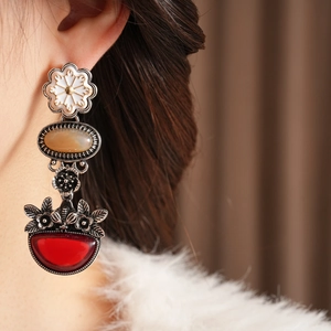 Detail of vintage flower drop earrings featuring colorful stones on a white fur collar