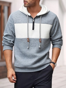 Detail of grey and white waffle knit fabric on a men's half-zip hooded sweatshirt