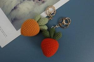 Detailed macro view of handmade crochet carrot keychains in orange and dark red wool yarn