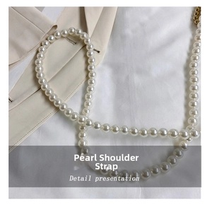 Close-up of white faux pearl shoulder strap with gold metal connectors on suit fabric
