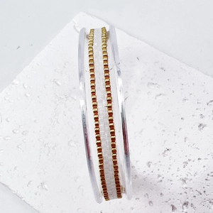 Macro detail of high-quality gold stainless steel chain wrapped on a clear plastic spool