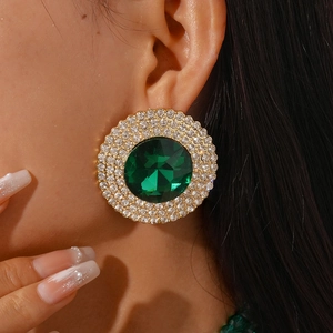 Close-up of vintage gold halo earring with a large green faceted stone and crystal rhinestones