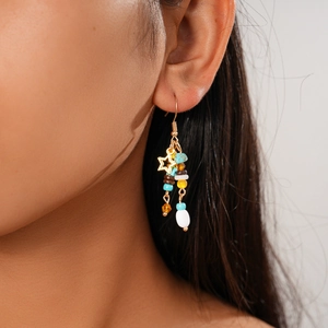 Close-up of beaded earrings with gold stars and multicolored tassels on a model