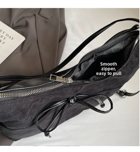 Detail view of the smooth metal zipper and matte black texture on a bow tote bag