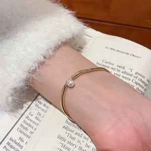 Détail du bracelet ouvert plaqué or 18k avec perle sur le poignet d'un mannequin