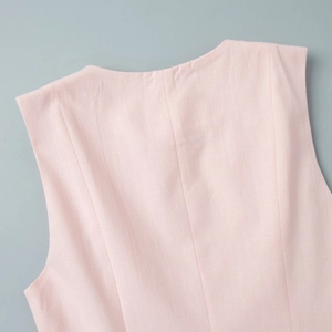 Détail du gilet en lin rose clair montrant la texture naturelle et les coutures soignées