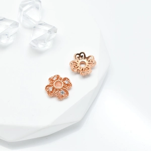 Rose gold five-petal flower jewelry beads with micro-set crystals on white stone base
