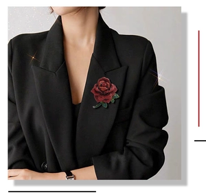 Detailed shot of a red crystal rose brooch pinned on a black suit lapel with green leaves