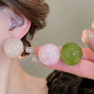 Close-up of oversized round resin earrings in cream, pink, and green glossy finish