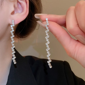 Close-up of elegant zircon fringe earrings with wavy silver tassels on model
