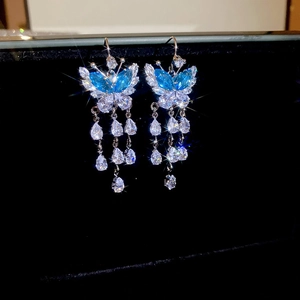 Detail of silver butterfly drop earring with blue zircon tassels on black background