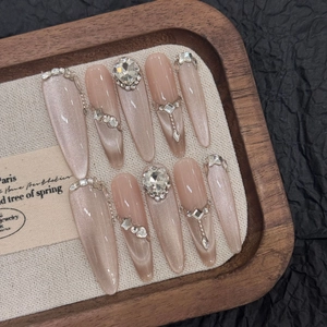 Detailed view of handmade cat eye nails with heart rhinestones on a linen tray