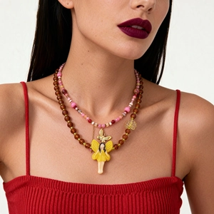 Boho layered necklace with pink beads, gold butterfly, and yellow fairy pendant on a model