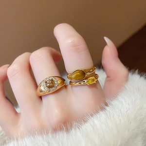 Close-up of gold plated oval tiger eye ring set with zircons on a model hand