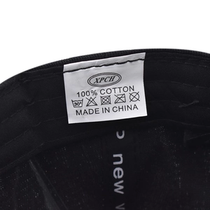 Detailed view of the 100% cotton fabric label and care instructions inside the black cap