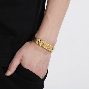 Gros plan d'un bracelet doré pour homme avec relief de dragon et motifs tressés