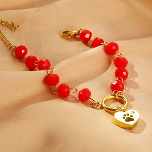 Red faceted bead bracelet with golden heart claw pendant on champagne satin background