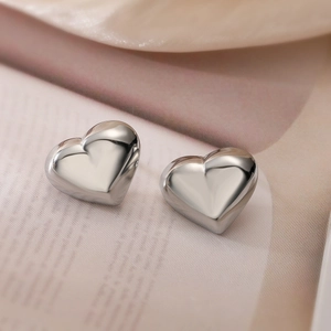Polished silver heart stud earrings shown on a vintage book for a minimalist look
