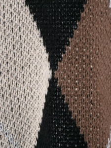 Macro shot of knitted diamond pattern texture in black, brown and beige colors