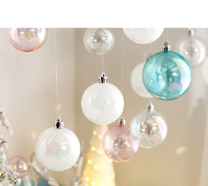Close-up of iridescent Christmas balls in white and pink hanging on a warm festive tree