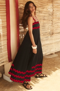 Close-up of black spaghetti strap dress featuring red ric-rac wavy trim details