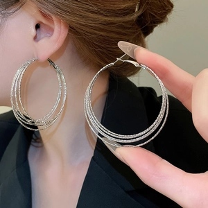 Detail of silver multi-layered hoop earrings with textured finish worn by a model