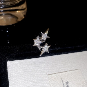 Gros plan de boucles d'oreilles triple étoile avec zircons brillants sur fond contrasté