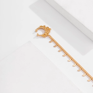 Detailed view of golden nose cuff featuring a long chain with crescent moon pendants