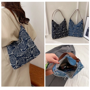 Detailed view of floral embroidery and interior of denim tote bag with brown strap