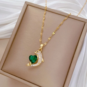 Macro detail of golden dolphin pendant with green heart stone and white zircons