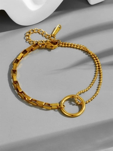 Dettaglio del bracciale in acciaio al titanio dorato con design a doppia catena e cerchio