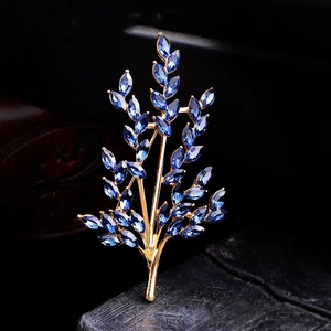 Detailed macro view of golden branch brooch with elegant marquise-cut blue crystals