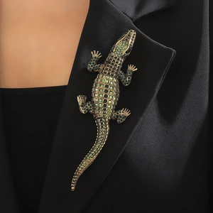 Elegant gold-tone crocodile brooch with green crystals on a black suit lapel