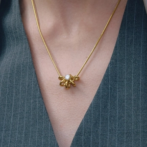 Gros plan d'un collier nœud doré avec zircon sur un costume à fines rayures