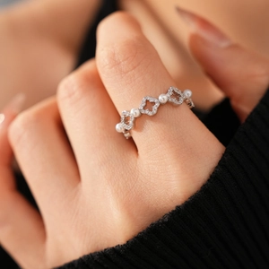 Détail d'une bague trèfle avec perles et zircons sur une finition argentée au doigt