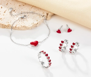 Macro shot of 925 silver jewelry set featuring red enamel heart charms on a stone surface