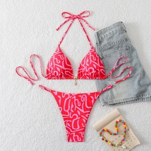 Red abstract print halter bikini set with star pendant on white plush background