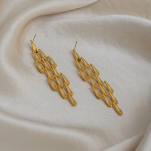 Détail de longues boucles d'oreilles dorées à pampilles avec pièces métalliques en larmes