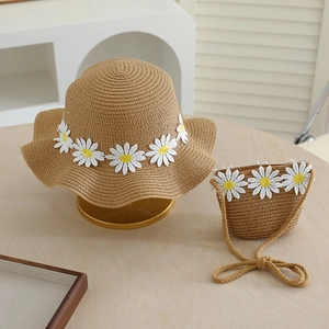 Close-up of woven straw hat and matching crossbody bag with white daisy floral appliqués