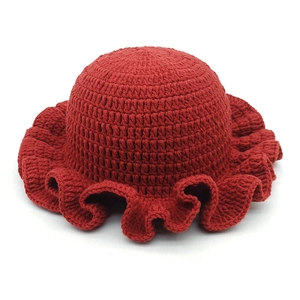Detailed view of dark red crochet knit hat featuring a wide ruffled brim and cozy texture