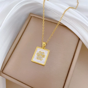 Macro shot of gold cat paw pendant featuring white shell inlay and sparkling crystals