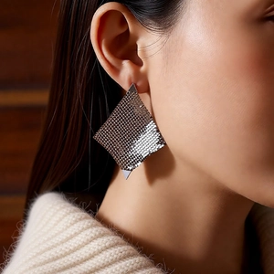Gros plan sur des boucles d'oreilles géométriques argentées à texture métallique