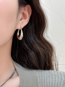 Close-up detail of silver water drop earrings worn by a model in a minimalist style