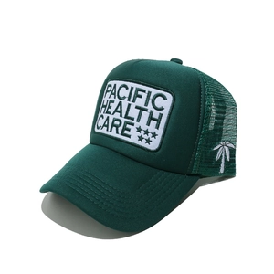 Detail of green mesh trucker hat featuring Pacific Health Care embroidery and coconut tree