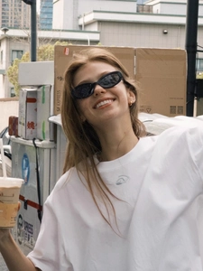Close-up of trendy black oval sunglasses with thin frames on a model for urban street style