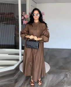 Detailed view of brown long-sleeved dress with puff sleeves and pleated chest design