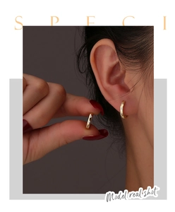 Vue détaillée des créoles dorées avec zircons présentées sur le profil d'un mannequin
