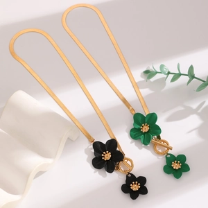Detail of floral necklaces with black and green enamel petals and golden toggle clasp