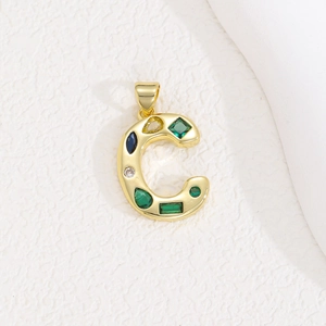 Macro shot of gold letter C pendant with colorful zircon stones and polished metal details