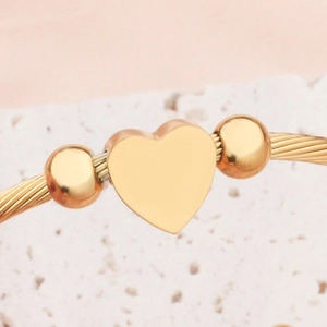 Golden heart charm cable wire open bangle with woven texture and dual bead accents